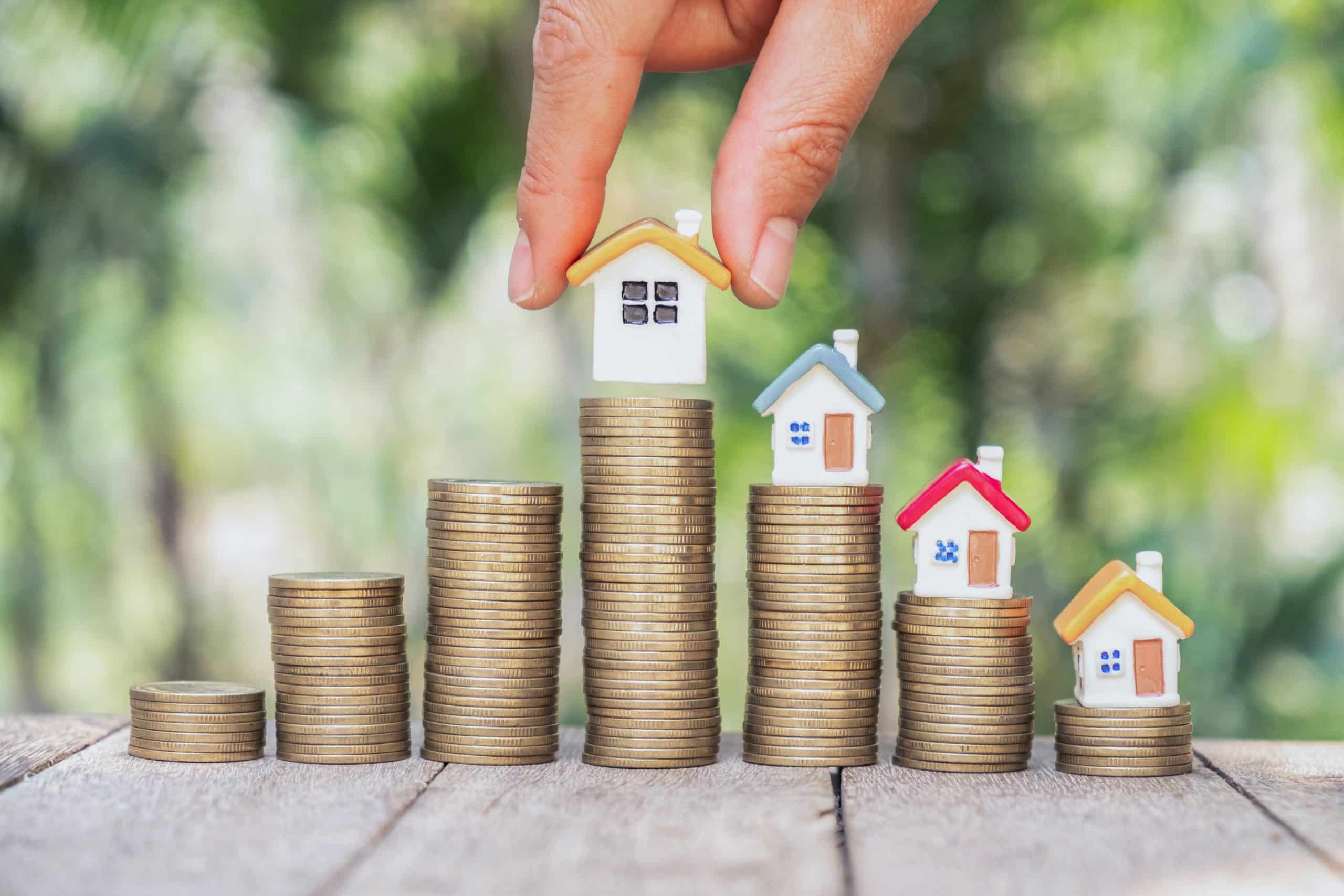 Human hand putting house model on coins stack,  planning savings money of coins to buy a home concept.