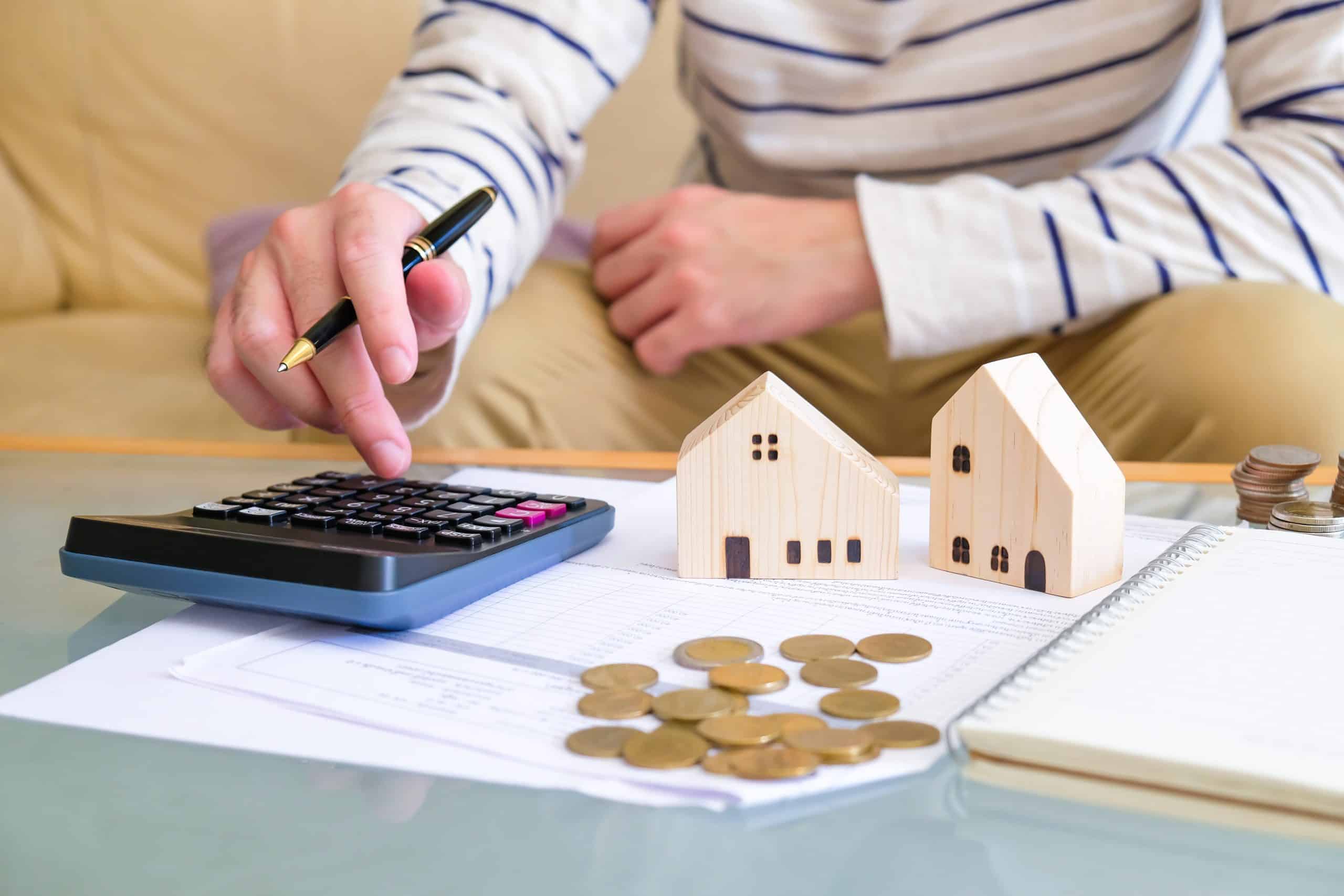 Selective focus at the wooden house with Asian men calculating his money for buy a new house or plan for home loan mortgage. Personal saving for home ownership.