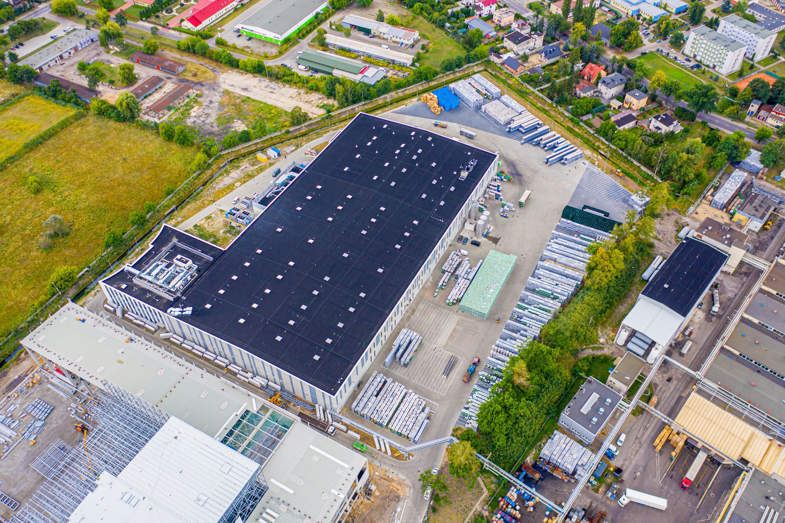 Aerial view of goods warehouse. Logistics delivery center in industrial city zone from above. Aerial view of trucks loading at logistic center. View from drone.